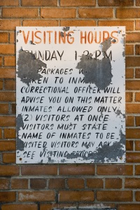 An old peeling hand painted sign explaining visitation rules and regulations.  This sign is from the entrance to the abandoned Marion County Prison in Marion, South Carolina.