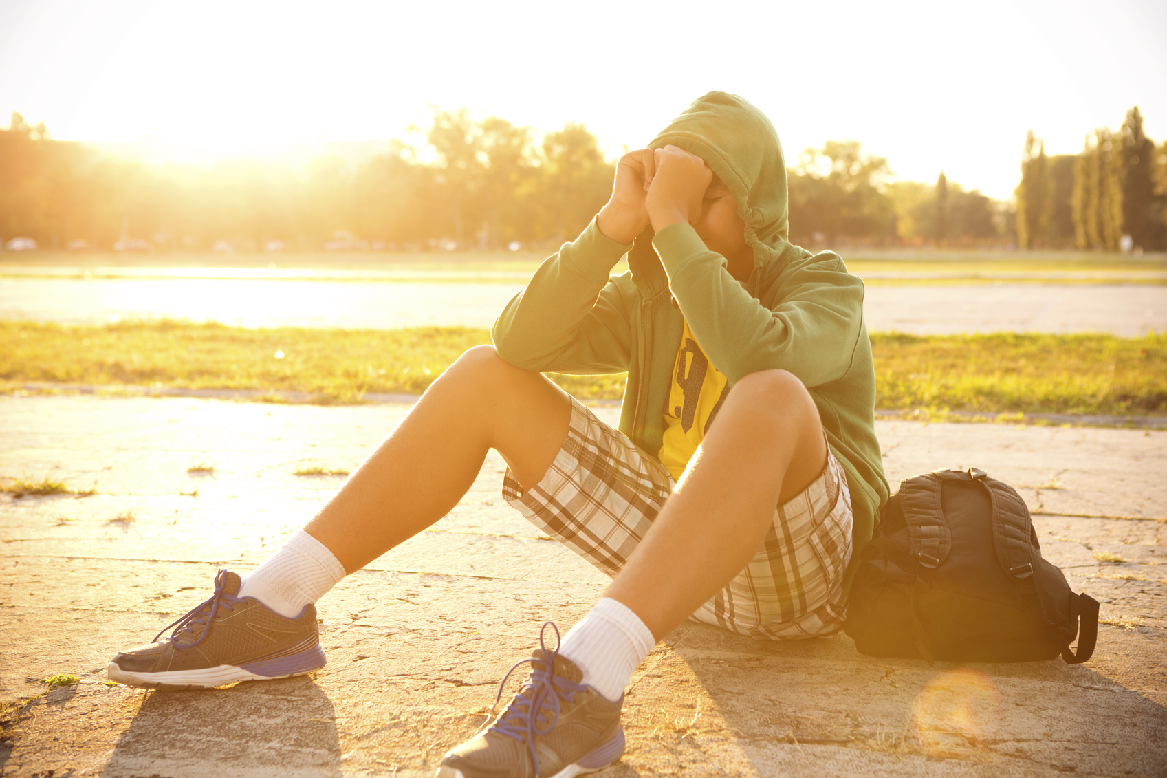 Teenage boy wearing hood sitting on ground