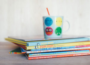 children's books stacked and a children's cup