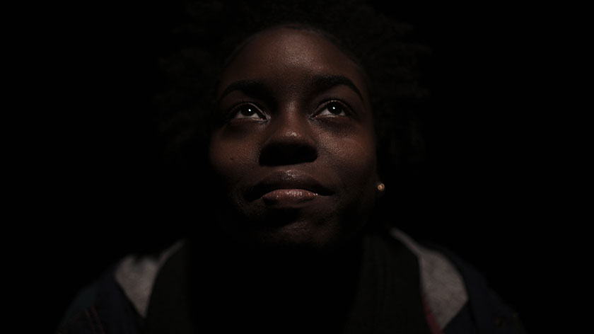 Woman looking up to the sky in a dark room. 