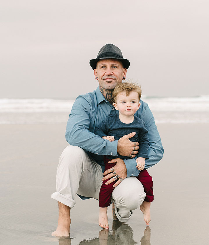 man holds son at beach