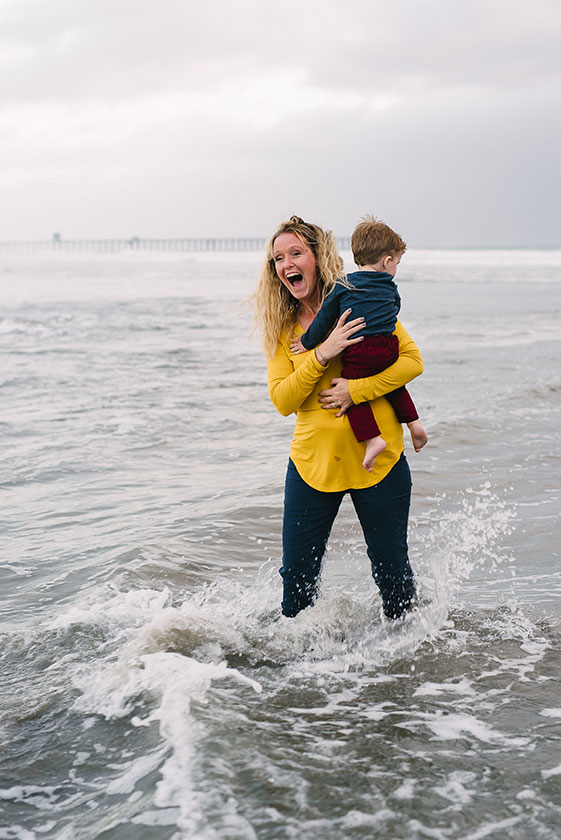 woman holds child in surf