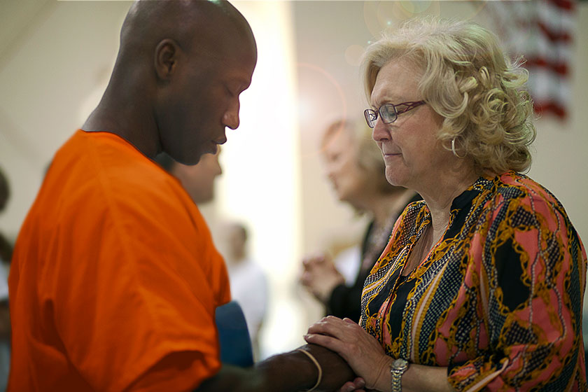 prisoner prays with volunteer