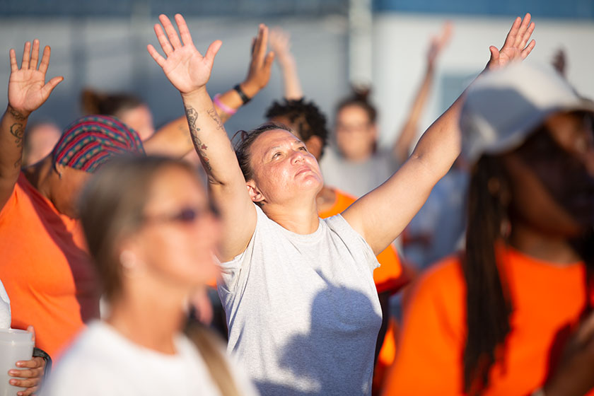 a prisoner raises her hands in worship