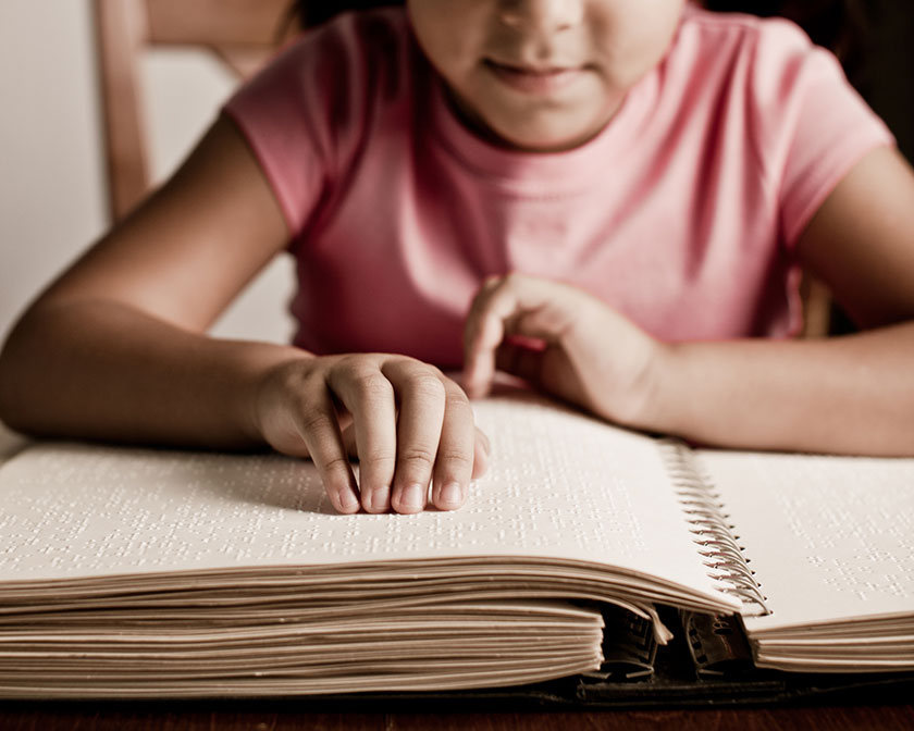 a young girl reads through a braille bible