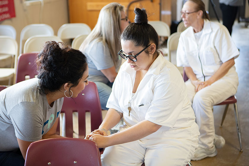 A Hope Event volunteer prays with a female prisoner