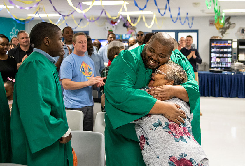 An academy graduate and current prisoner hugs a friend