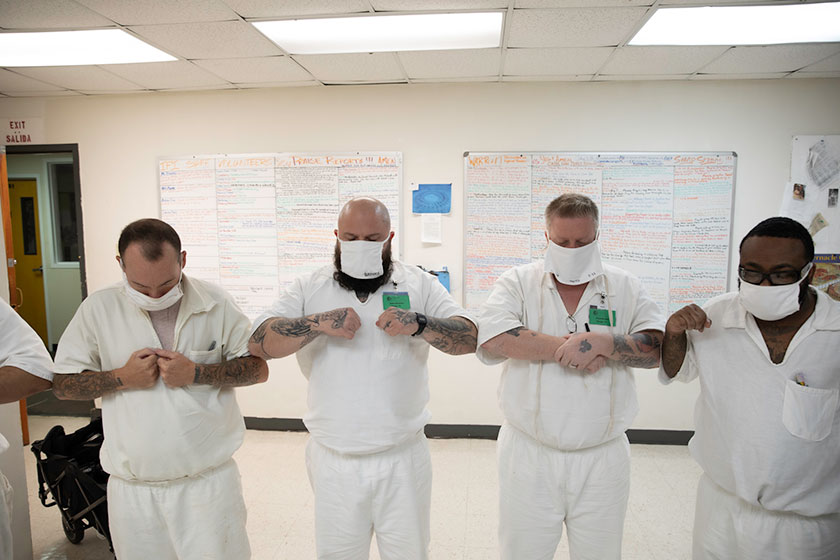 incarcerated men wearing face masks and practicing social distancing