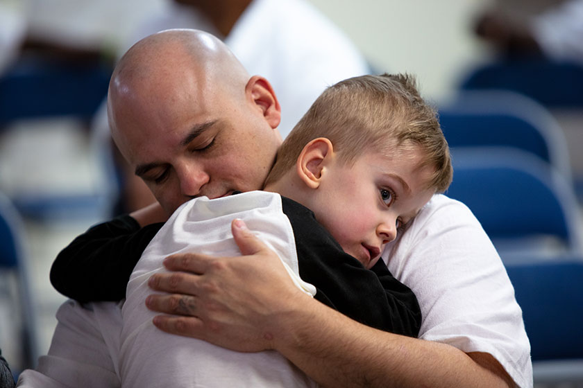 an incarcerated father hugs his son