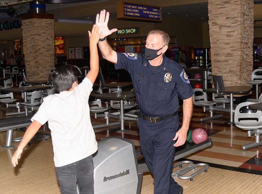 A Las Vegas police officer high fives a young boy at the 2020 Bowling with Blue event.