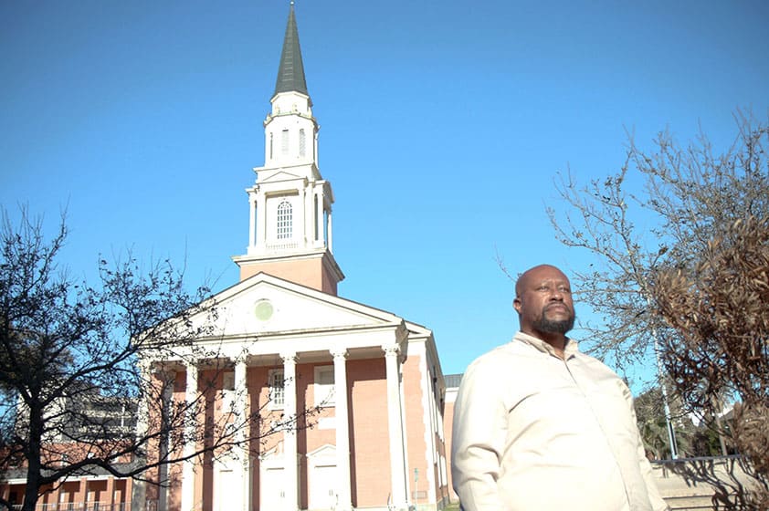 black man stands in front of a church