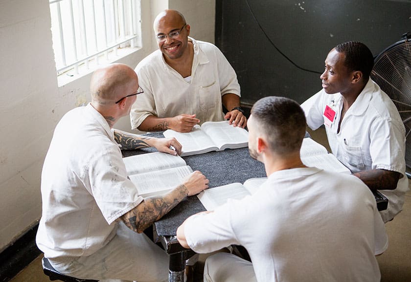 black and white incarcerated men study the bible together