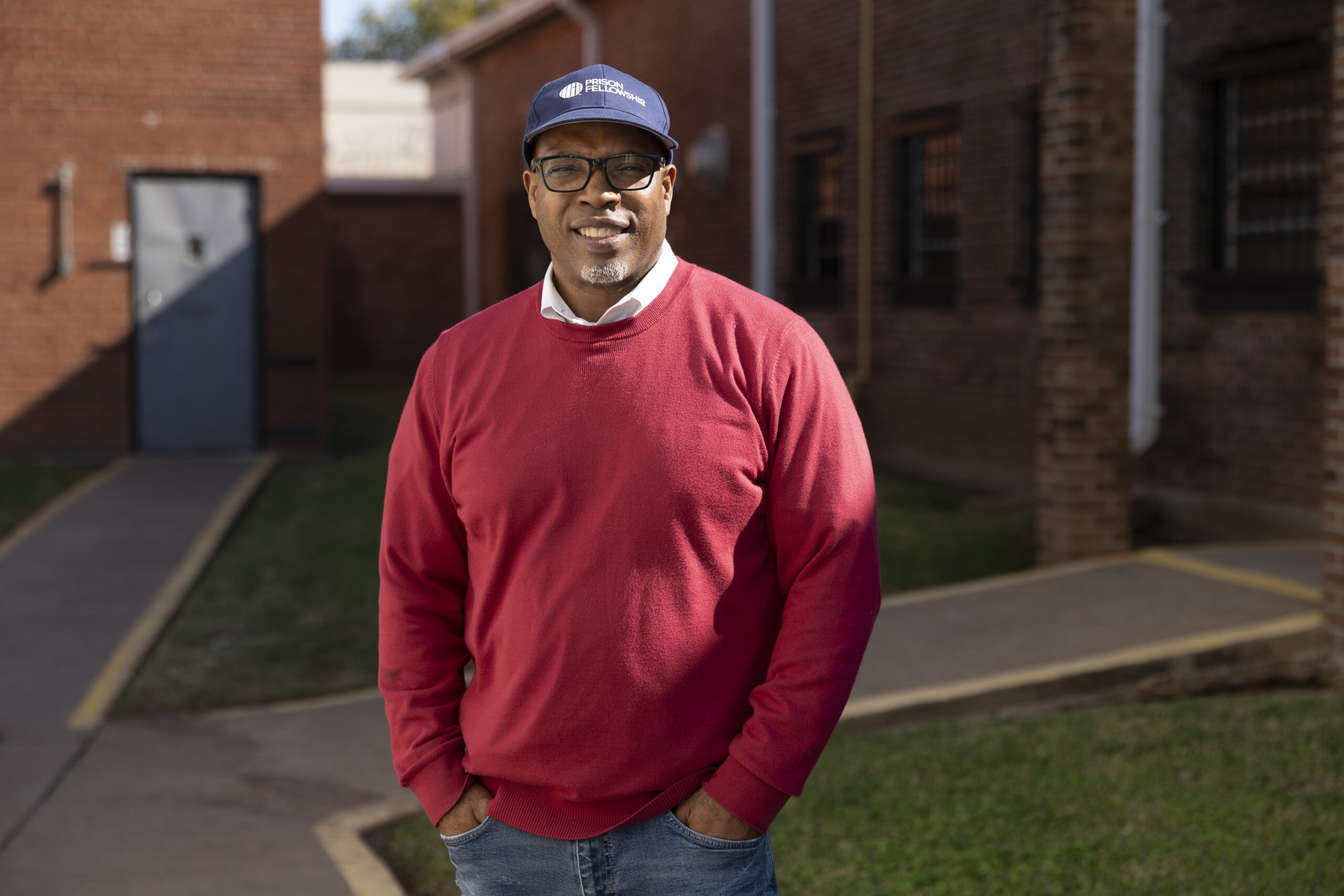 Darryl wears a red sweater and cap